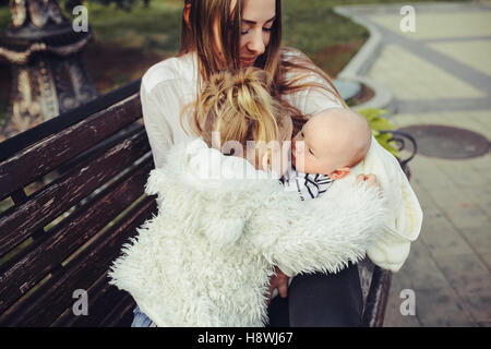 Mutter und zwei Töchtern Ausruhen auf einer Bank Stockfoto