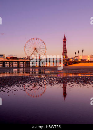 Blackpool Tower und Central Pier mit Spiegelung im Wasser am Strand bei Sonnenuntergang, Lancashire, UK. Stockfoto