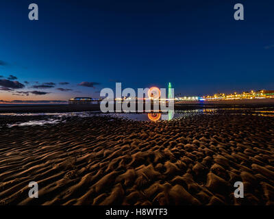 Blackpool Tower und Central Pier mit Reflexion der Beleuchtung im Wasser am Strand, Lancashire, UK. Stockfoto