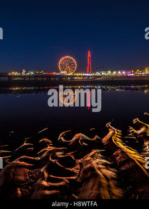 Blackpool Tower und Central Pier mit Reflexion der Beleuchtung im Wasser am Strand, Lancashire, UK. Stockfoto