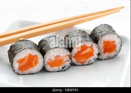 Vier Kombu Lachs Sushi Reis aufgewickelt und Seegras als Vorspeise serviert, mit Stäbchen Stockfoto