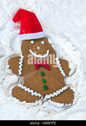 Ginberbread Mann mit Weihnachtsmütze weißes Mehl einen Schneeengel machen Stockfoto