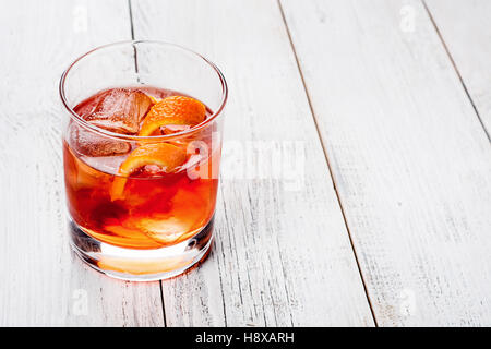 Glas mit dunkel orange Getränk. Zitronenschale und Eis. Negroni mit bitteren und Wermut. Stockfoto