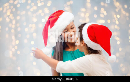 glückliche Mutter und kleine Mädchen in Santa Hüte Stockfoto