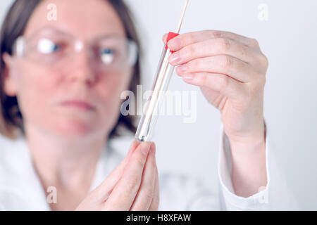 Weibliche Labor-Spezialist hält Reagenzglas mit Wattestäbchen, medizinische Wissenschaft professionelle Aufnahme Probe für Laboranalysen. Stockfoto