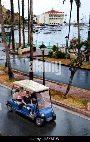 Blick auf Avalon Hafen und Casino mit Elektrofahrzeugen an einem regnerischen Tag auf Catalina Island vorbeifahren. Stockfoto