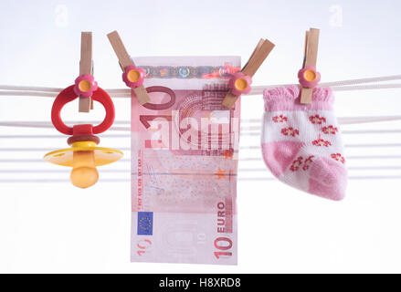 Dummy, Babysocken und Geldschein an Wäscheleine, symbolisches Bild für Kindergeld Stockfoto