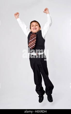 Junge, 8, gekleidet wie ein Geschäftsmann, springen Stockfoto