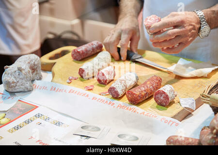 Mann schneiden gewürzte Salami auf Verkauf während Alba weiß Trüffelmesse in Alba, Italien Stockfoto