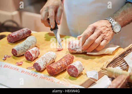 Mann schneiden gewürzte Salami auf Verkauf während Alba weiß Trüffelmesse in Alba, Italien Stockfoto