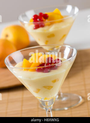 Creme-Dessert mit frischen Pfirsich und roten Beeren. Stockfoto