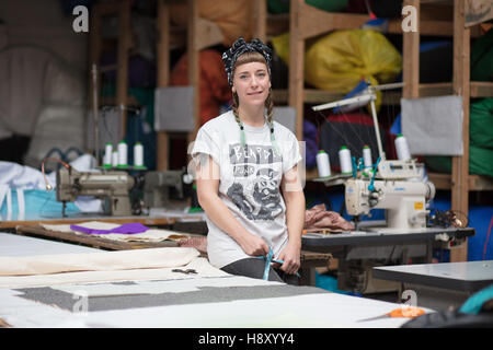 Porträt einer jungen tätowierte Schneiderin in einer Fabrikumgebung Stockfoto