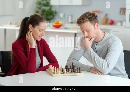 glückliches junges Paar spielen Schach im Wohnzimmer Stockfoto