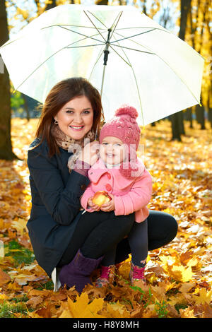 Frau mit Kind Mädchen unter Dach im Herbst Stadtpark, glückliche Familie Stockfoto