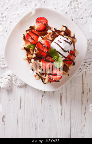 Leckere Waffeln mit Erdbeeren, Schlagsahne und Schokolade Zuckerguss schließen sich. Vertikale Ansicht von oben Stockfoto