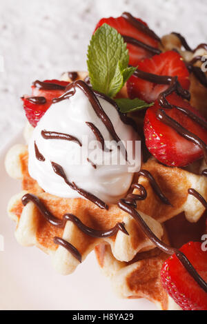 Leckere Waffeln mit Erdbeeren, Schlagsahne und Schokolade Zuckerguss Makro. vertikale Stockfoto