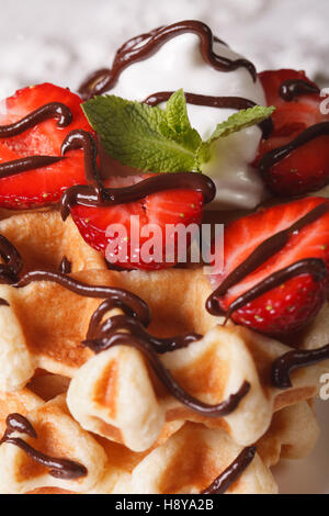 Belgische Waffeln mit Erdbeeren, Schlagsahne und Schokolade Topping Makro. vertikale Stockfoto