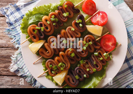 Kebab aus Calamari auf Spieße mit Gemüse auf einem Teller. horizontale Ansicht von oben Stockfoto