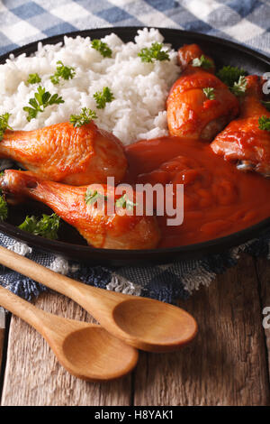 Thai-Küche: Hähnchenkeulen in würziger Chilisauce Sriracha und Reis Nahaufnahme auf einer Platte gebacken. Vertikal Stockfoto