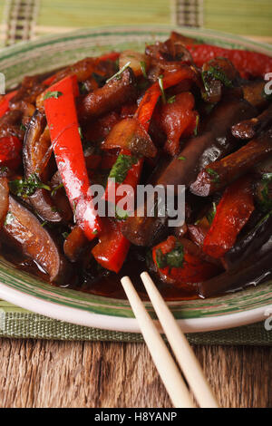 Unter Rühren braten, asiatische Auberginen, Paprika, Zwiebeln und Tomaten Nahaufnahme auf einer Platte. vertikale Stockfoto