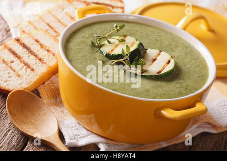 Zucchini-Suppe-Püree in einer Nahaufnahme gelben Topf und Toast auf den Tisch. horizontale Stockfoto