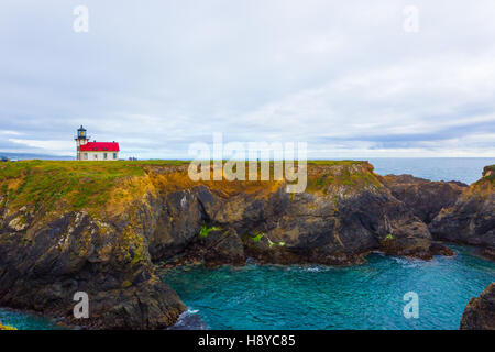 Fernsicht auf felsigen Klippen über dem Meer Bucht und der historische Leuchtturm von Point Cabrillo Light Station an einem trüben Abend in mir Stockfoto