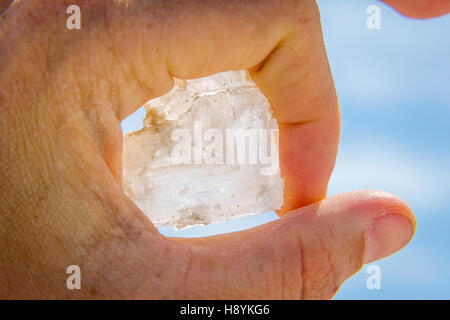 Halten große Salzkristall in der hand gegen blauen Himmel Stockfoto