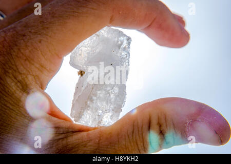 Halten große Salzkristall in der hand gegen blauen Himmel Stockfoto