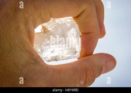 Halten große Salzkristall in der hand gegen blauen Himmel Stockfoto