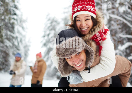 Glücklicher Kerl hält seine Freundin auf Rücken und beide lachen Stockfoto