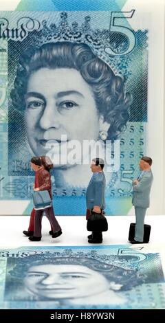 Miniatur-Figuren zu Fuß vor einer fünf-Pfund-Note. Stockfoto