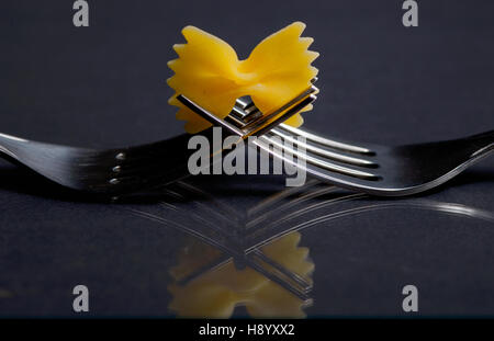 Pasta Farfalle auf einer Gabel auf schwarzem Hintergrund Stockfoto