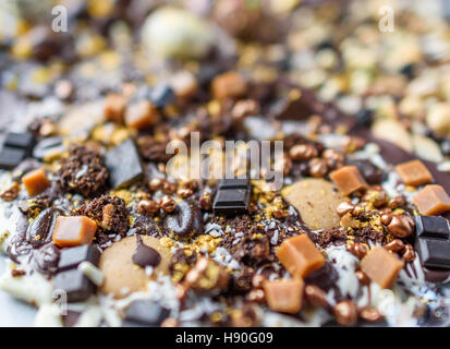 Eine glitzernde Platte aus geschmolzener Schokolade, Fondant und Kaffeebohnen hautnah Tiefenschärfe. Stockfoto