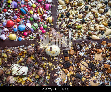 Ostern explosive, abstrakte Mischung aus Schokolade, Bonbons und Nüssen um die Form eines Kreuzes. Stockfoto