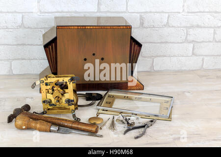 Vintage Jugendstil Holz Kaminuhr in Stücken mit Werkzeugen mit alte weiße Ziegel Wand Effekt Hintergrund Stockfoto