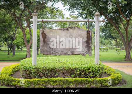 Im Alter von Holzbrett mit Leerzeichen hängen weiße Balken und Stangen von alten Kette im öffentlichen Park von Bush und grünen Bäumen umgeben. Stockfoto