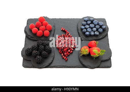 Superfrüchte, Heidelbeeren, Himbeeren, Brombeeren, Erdbeeren und Granatapfel Herzform und lange Schiefer Board isoliert Stockfoto