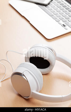 Kopfhörer und Laptop auf hölzernen Schreibtisch Tisch. Musikkonzept Stockfoto
