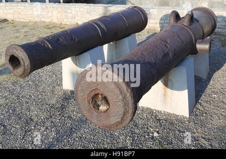 Zwei alte rostige Marine-Artillerie-Kanonen auf weißen steinernen Sockel Stockfoto