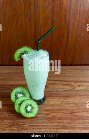 Gesunden grünen Smoothie aus Kiwi mit grüne Strohhalme auf einem Holztisch hergestellt. Stockfoto