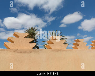 Rosa Stadtmauern gegen strahlend blauen sonnigen Himmel mit Wolken und Palmen, Marrakesch, Marokko, Nordafrika Stockfoto