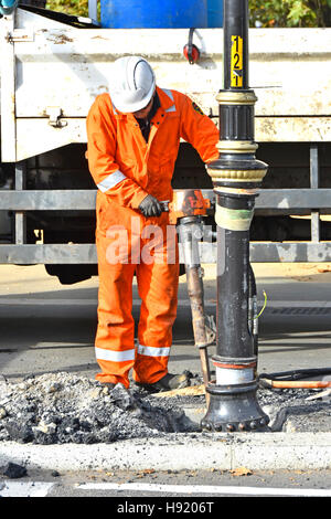 Arbeiter arbeiten auf Straßenarbeiten Reparatur Job Druckluft Presslufthammer Ausrüstung Werkzeug bricht um Straßenlaterne Post London England VEREINIGTES KÖNIGREICH Stockfoto