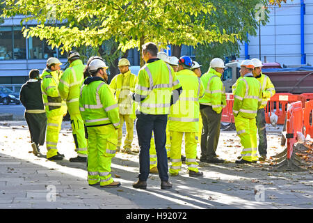 Group Manager Aufsichtsbehörden Ingenieure Vorarbeiter Vermesser treffen neben dem großen Baustellen-Projekt-Firmen-Logos entfernt London England UK Stockfoto