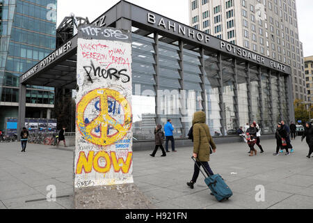 Fußgänger vorbei gehen. Berliner Mauer Abschnitt mit Peace Symbol und Graffiti am Bahnhof Potsdamer Platz, Berlin, Deutschland, EU KATHY DEWITT Stockfoto