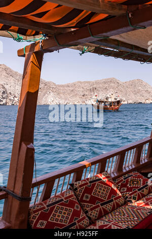 Vertikale Ansicht einer traditionellen arabischen Dau, die durch die Halbinsel Musandam segelt, von einer anderen Dau mit Majilis-Kissen, dem Sultanat von Oman, aus gesehen Stockfoto