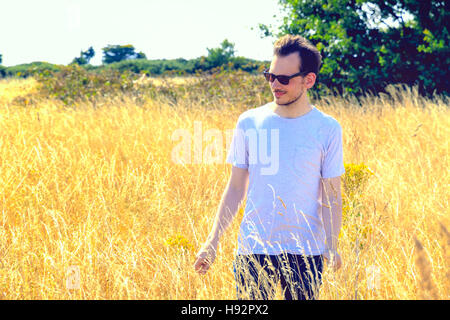 Junger Mann genießen Sonne mit Sonnenbrille im Bereich von golden Grass Konzept einsetzbar Stockfoto