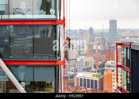 London, UK - 20. September 2016 - Fensterputzer arbeiten an einem Hochhaus mit Stadtbild im Hintergrund Stockfoto