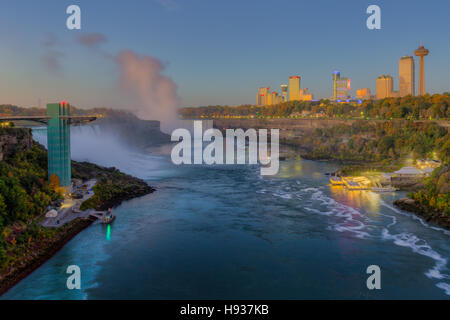 Der Niagara River, darunter die American Falls, die Horseshoe Falls und die Skyline von Niagara Falls, Ontario kurz vor Sonnenaufgang. Stockfoto