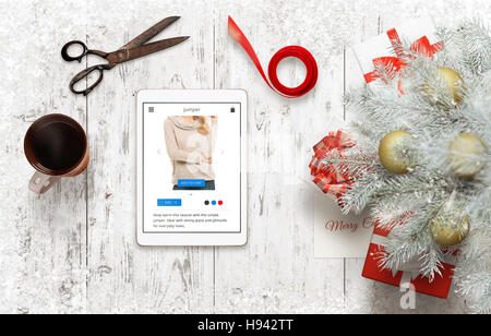 Geschenke für Weihnachten und das neue Jahr vorbereiten. Shopping Geschenke online mittels Tablet. Neben dem Weihnachtsbaum mit Geschenken und Zubehör für Stockfoto