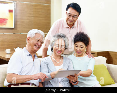 zwei aktive senior asiatische Paare betrachten Tablet-Computer, glücklich und lächelnd Stockfoto